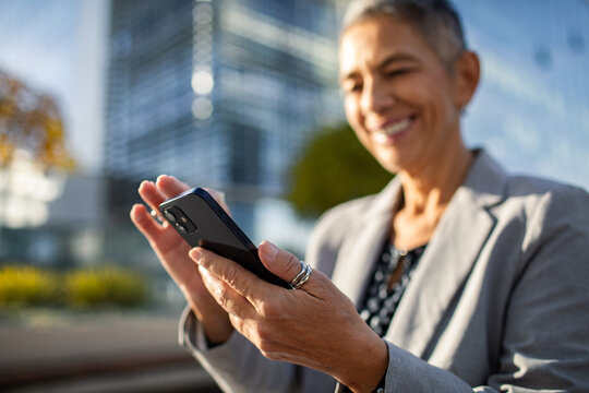 Smiling professional woman using smartphone in city