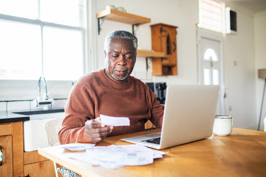 Senior man managing finances at kitchen table