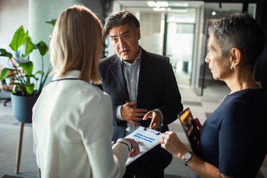 Business colleagues discussing report in modern office hallway