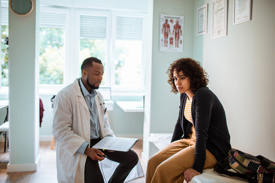 Doctor consulting concerned patient in clinic exam room