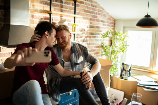 Happy couple taking selfie while moving in new home kitchen