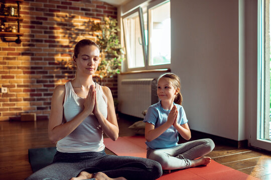 Mother and daughter meditating together in a living room