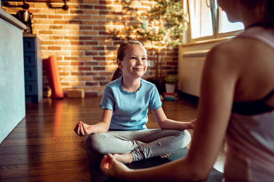 Smiling girl practicing yoga with mother at home