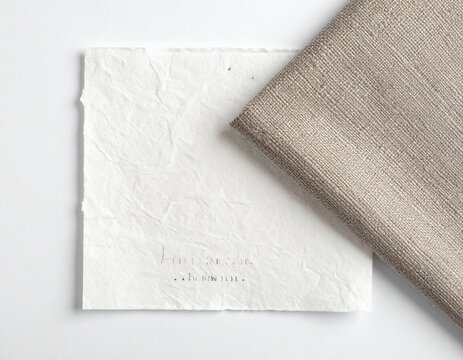 Tela de lino natural doblada sobre superficie blanca con sombra lateral