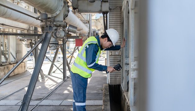 Engineer performs predictive maintenance with a thermal camera on industrial equipment, inspecting lower access points to improve safety, reliability, fault detection, and uptime.