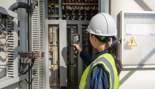 Engineer performs industrial monitoring with a thermal camera inside an electrical control cabinet, supporting safety, reliability, diagnostics, and maintenance checks.