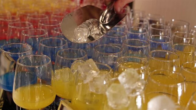 Bartender prepares a colorful cocktails at a party, adding ice cubes to the glasses, mixing vibrant ingredients to create a refreshing drink that adds energy, fun, and great vibes to the celebration