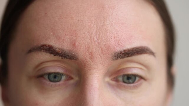 Woman showing her healing eyebrows after permanent makeup. Closeup. 4K