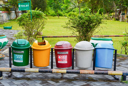 Rows of plastic trash cans in green, yellow, red, grey, and blue for environmental waste management. 