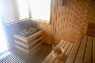 Wooden sauna interior with a heated stove and bucket for a steam bath
