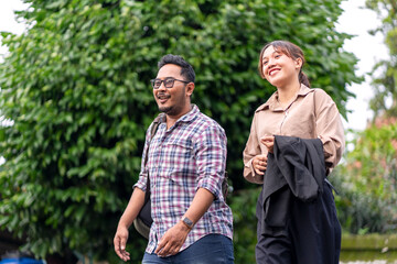 Obraz premium Asian Couple Walking Together on City Street with Green Trees