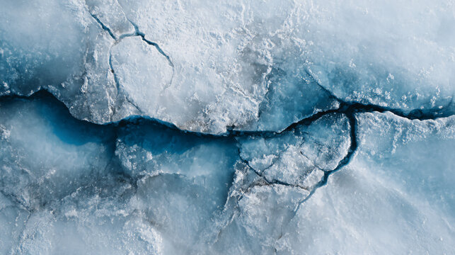 Cracked ice surface with deep fissures showcasing natural textures and blue-tinted frozen layers.