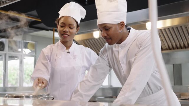Two African chefs preparing food together in a busy restaurant kitchen