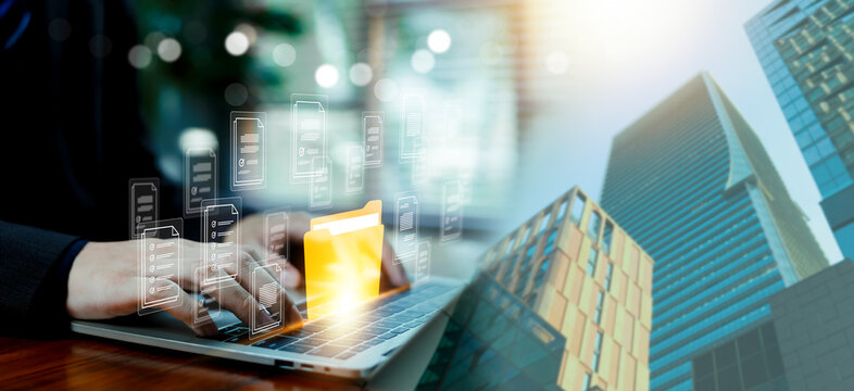 Business professional using laptop with digital document management interface virtual file icons over modern city office buildings Concept of cloud storage data organization, smart business technology