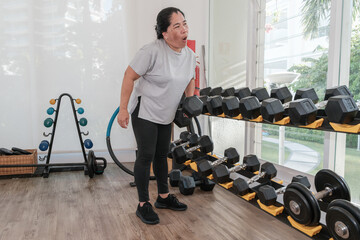 Woman lifting weights in a gym while focused on her workout routine during daylight hours