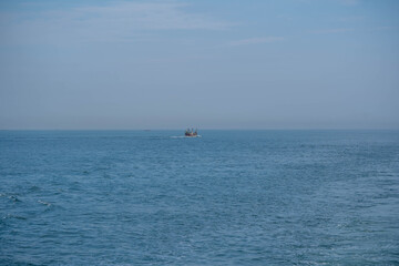 Naklejka premium Fishing boat sailing calm blue ocean water horizon
