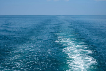 Ship wake creating foamy trail on blue ocean