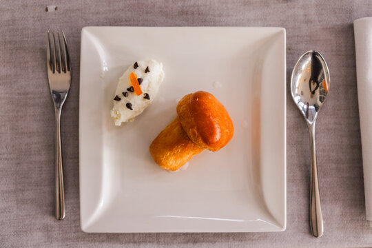 Bab&agrave; tradizionale napoletano accompagnato da crema di ricotta condita con gocce di cioccolato fondente e arancia candita servito come dessert in un ristorante elegante