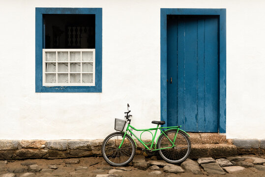 Green bicycle against white and blue house