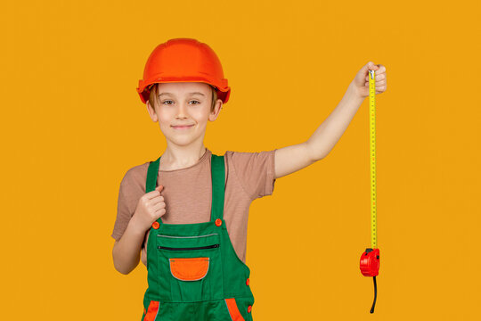 Boy with a measuring tape. Child dressed as builder with ruller in hands. Child dressed as a workman builder. Little boy wearing helmet. Little builder in hardhats, building helmet, hard hat