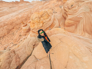 Naklejka premium A woman is standing on a rocky mountain, wearing a black jacket and sunglasses