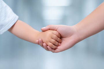 Close up of adult hand gently holding child hand, symbolizing care, protection, and trust in calm and soft light setting