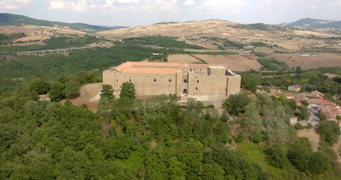 Aerial closeup of Lagopesole Castle, located in Basilicata, Italy. It is a medieval fortification dating back to the time of Frederick II. The medieval fortress is surrounded by dense green forest.