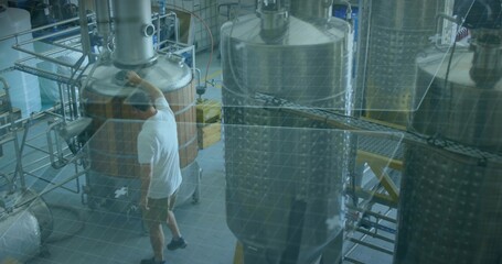 Reaching worker in white tee and khaki shorts checking wooden kettle on brewery floor, copy space © vectorfusionart