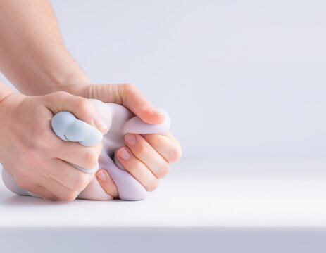 Hand squish soft silicone sensory toy providing tactile stress relief feeling calm and relaxed. Person gently pressing fluffy dough material for therapeutic psychological benefit and comfort