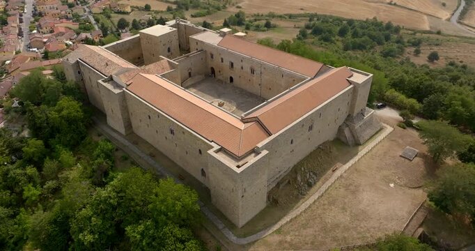 Aerial closeup of Lagopesole Castle, located in Basilicata, Italy. It is a medieval fortification dating back to the time of Frederick II. The medieval fortress is surrounded by dense green forest.
