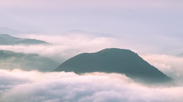 A scenic view of Datun Mountain in Taipei, Taiwan, during a spring morning with thick clouds and mist rolling over the peaks.