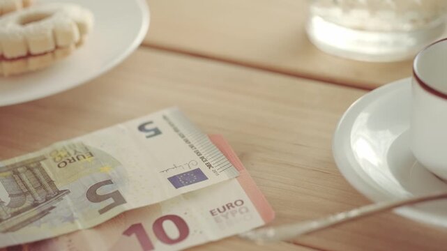 Female hand placing euro banknotes on white saucer. Restaurant bill payment or tipping concept, Financial transaction in dining setting, service industry