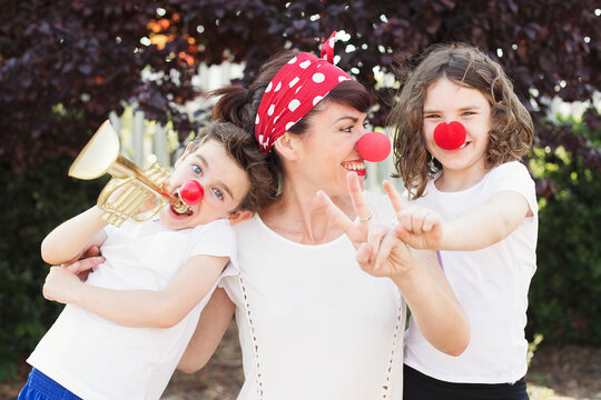 Portrait of a happy woman with her son and daughter standing in a garden on a summer day dressed as clowns