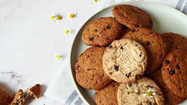 Sweet chocolate chip cookies and a refreshing glass of milk rest on a patterned napkin over a light marble surface, perfect for a treat.