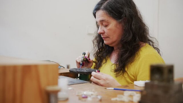 Woman jeweler soldering a piece of jewelry with a gas torch