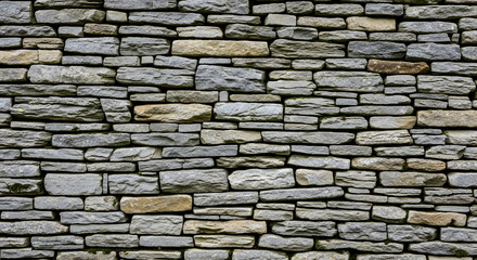Obraz premium A close-up view of a stone wall with various grey and brown stones.