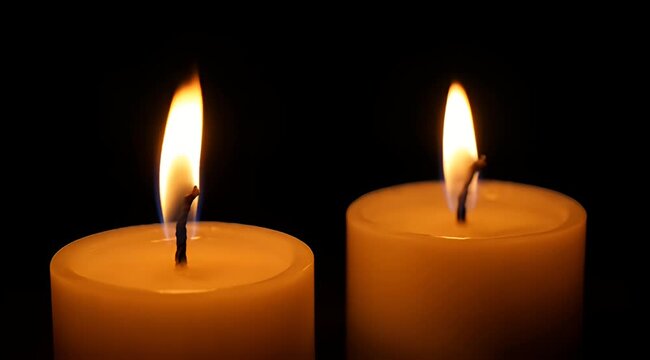 Two serene candles illuminate a dark space with gentle flickering flames