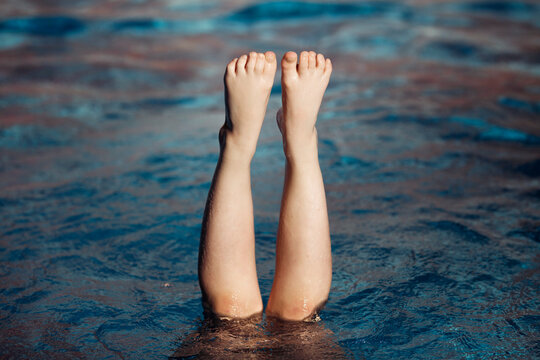 Close-up of a girl diving into a swimming pool with her legs sticking out of the water