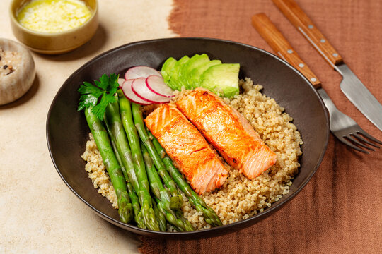 Plate with Salmon fillet, Quinoa and Asparagus, redish and avocado on a  beige table with mocha colour textile.