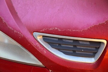 Fototapeta premium Car paint coat sun damage. Peeling sun damaged paint surface in a 20 year old compact red car in Spain.