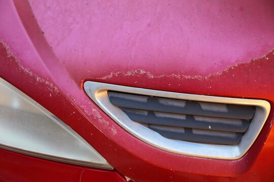 Car paint coat sun damage. Peeling sun damaged paint surface in a 20 year old compact red car in Spain.
