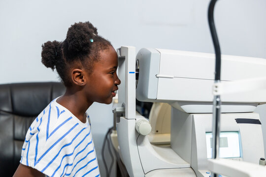 Young African girl child receiving an ocular examination using autorefractor machine in a clinic