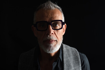 portrait of a mature man looking at camera on black background