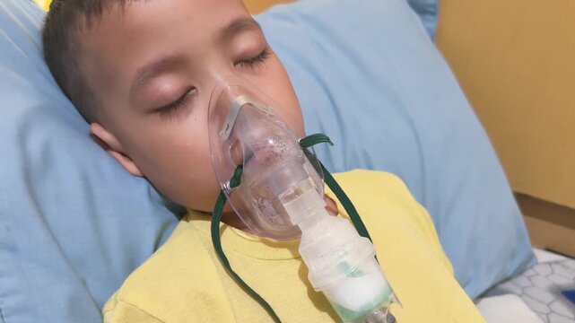 Young child receiving respiratory treatment with nebulizer mask while resting. Medical therapy for breathing problems and respiratory illness in children.
