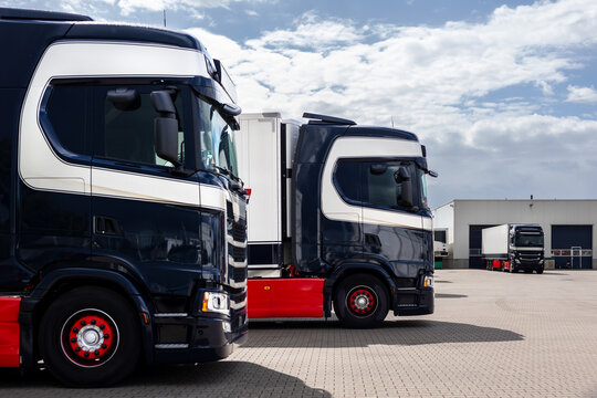 Modern blue cargo truck delivery van parked logistics warehouse center complex building exterior bay. Semi-trailer lorry unload goods distribution blue sky. Cargo storage facility industry building