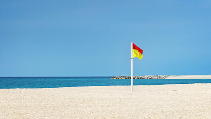 Lifeguard flag stands on the beach during a sunny day at the seaside © Sergey