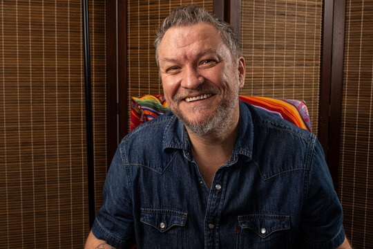 A 48 year old Brazilian man, sitting in a rocking chair and telling a funny story_d.