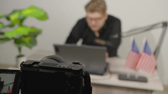 Focused young male blogger working on laptop with professional camera