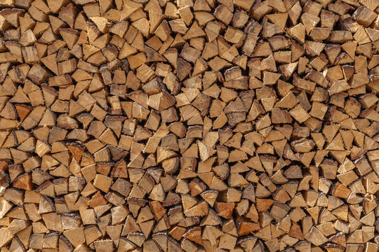 Detailed texture of a large wall of split firewood logs stacked neatly in an alpine village
