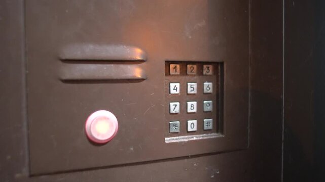 An intercom system is activated, producing sharp electronic ringing sounds in a building lobby. The call signal is clear and noticeable. The intercom panel shows numbers and buttons.